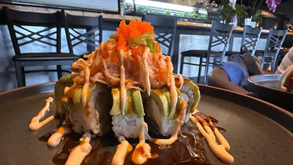 a plate of sushi covered in red and orange sauce