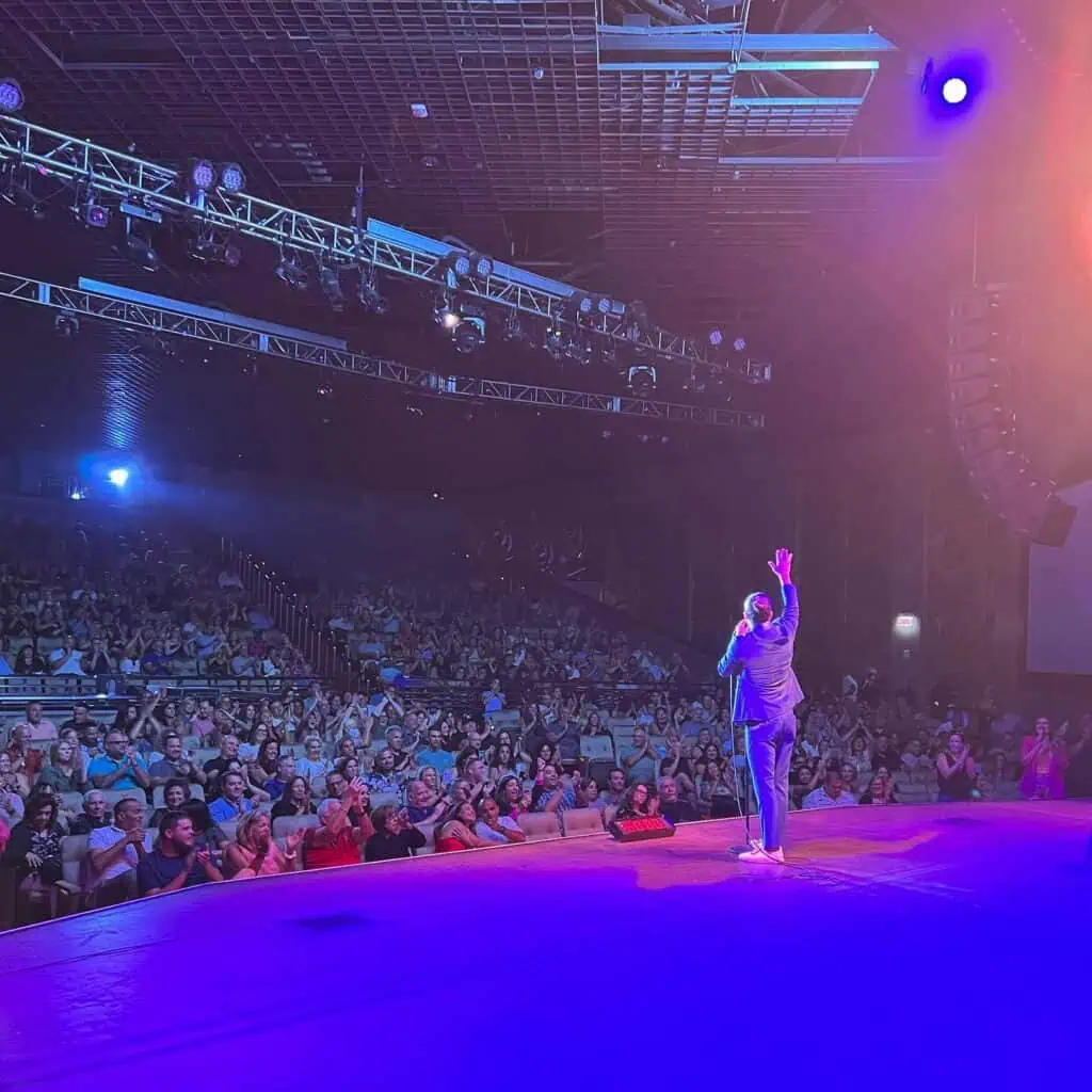 Eric D'Alessandro waving to a packed theater