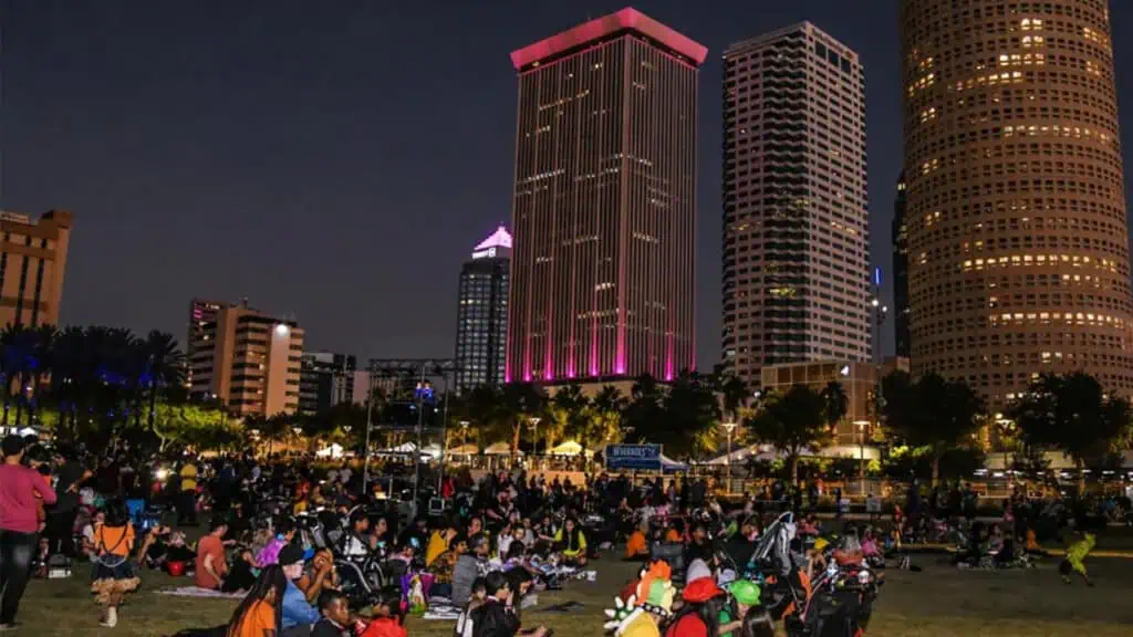 a group of people enjoy a movie I the park at night