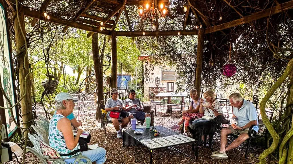 a group of people chat under a gazebo in a garden