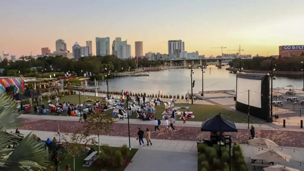 a large film screen et up in a waterfront area with multiple viewers