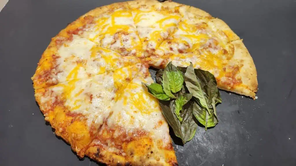 a large cheese pizza featuring spinach