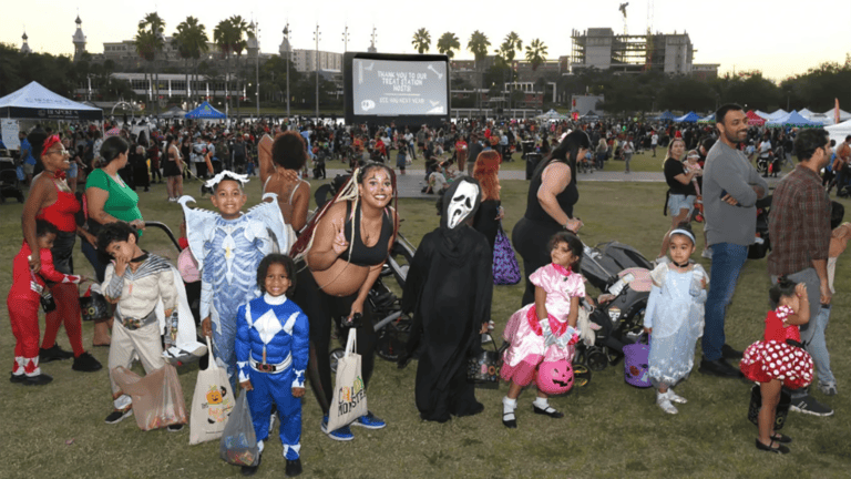 a group of people in Halloween costumes enjoy a movie in the park