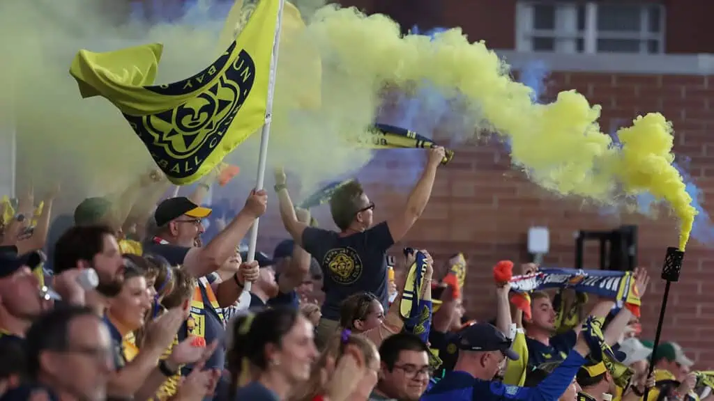 a large crowd wavs flags during the opening of a new pro soccer team