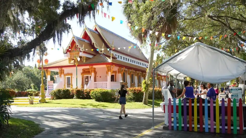 exterior of a buddhist temple in the day time with market vendor tents set up outside