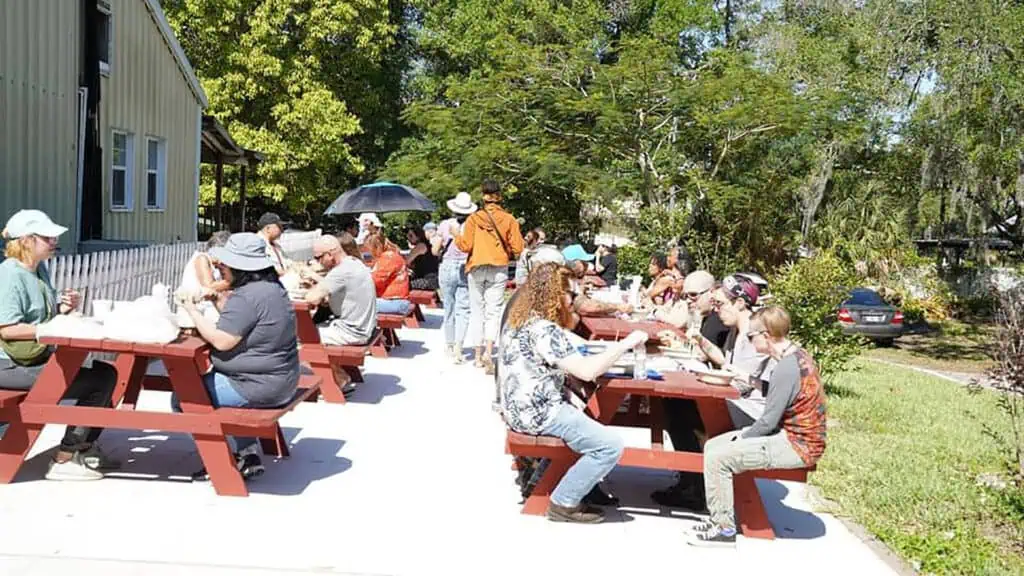 people dine at red picnic tables outside a Buddhist Temple