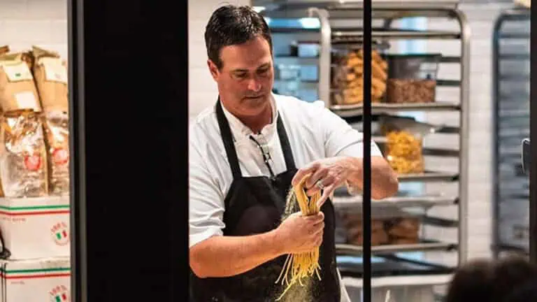 A chef handles pasta in an open kitchen