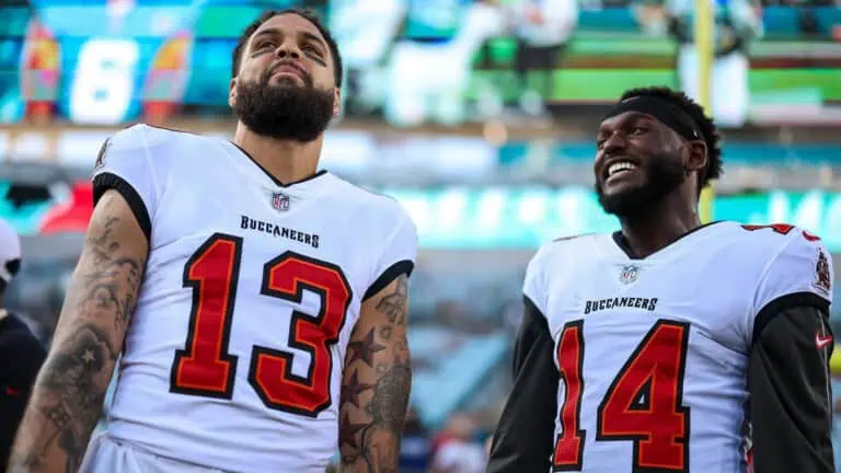 two football players pose in white uniforms