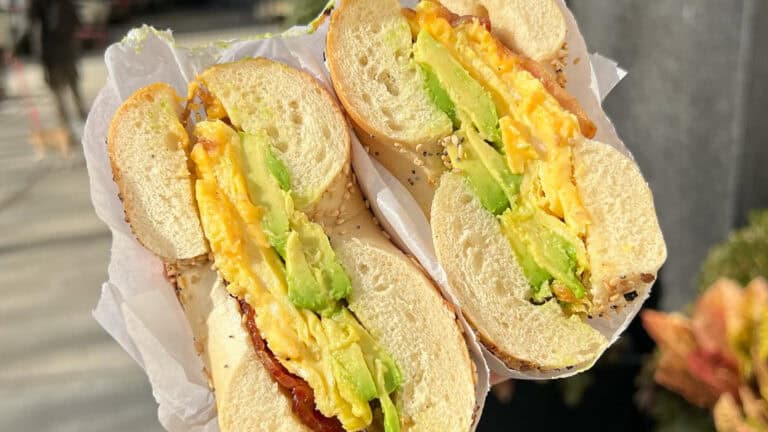 a bagel sandwich with avocado and egg