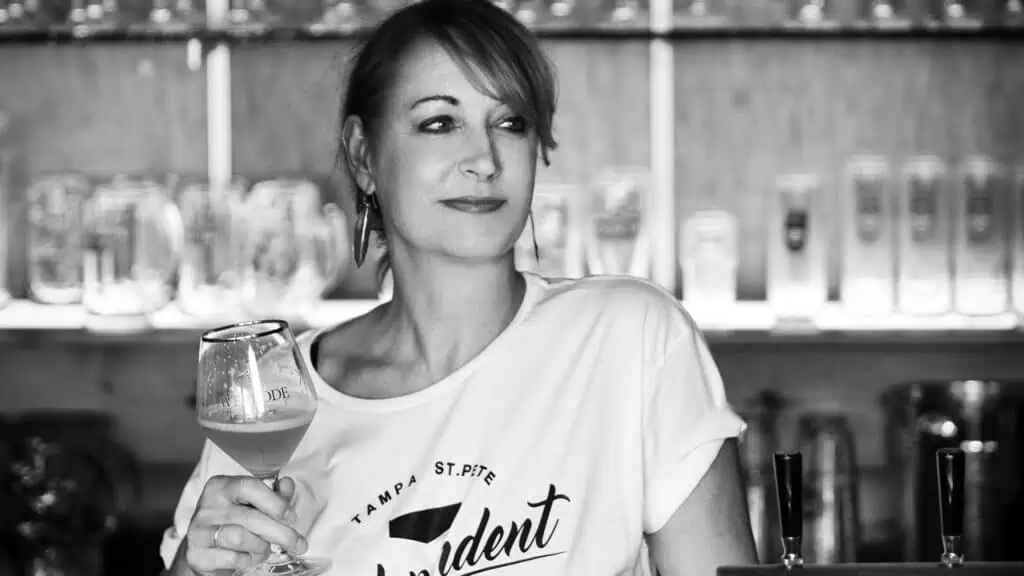 black and white photo of a woman holding a wine glass behind a bar