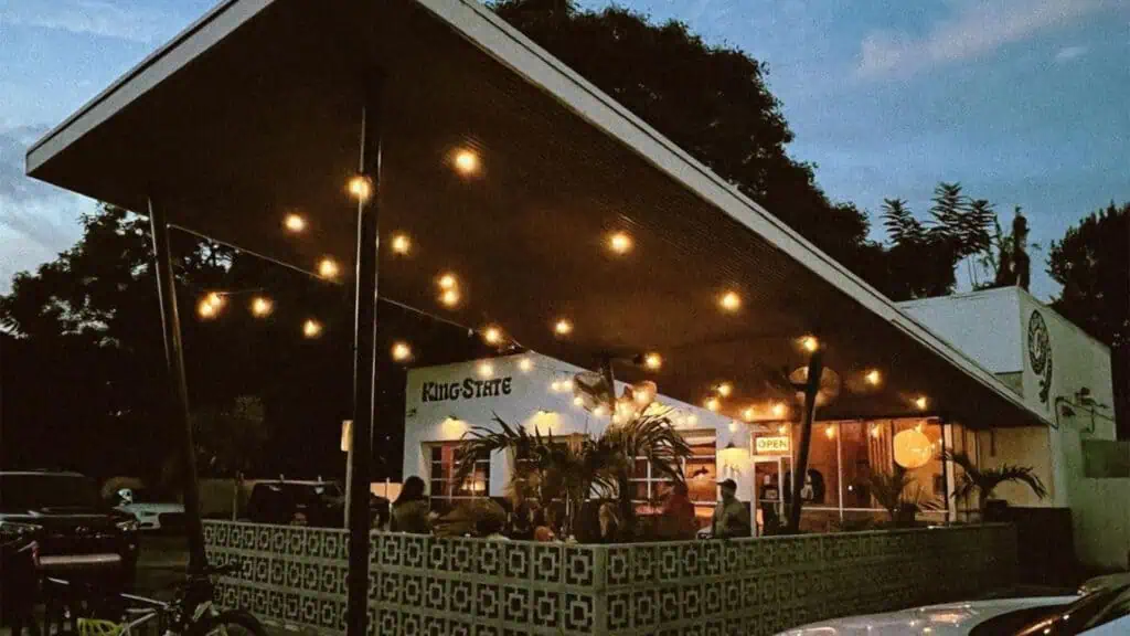 exterior of a cafe at night with people enjoying drinks 