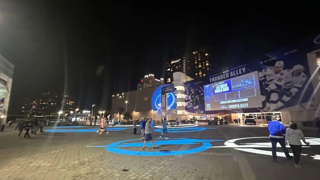 blue and white lightning bolt graphics projected on a sidewalk area outside of an arena 