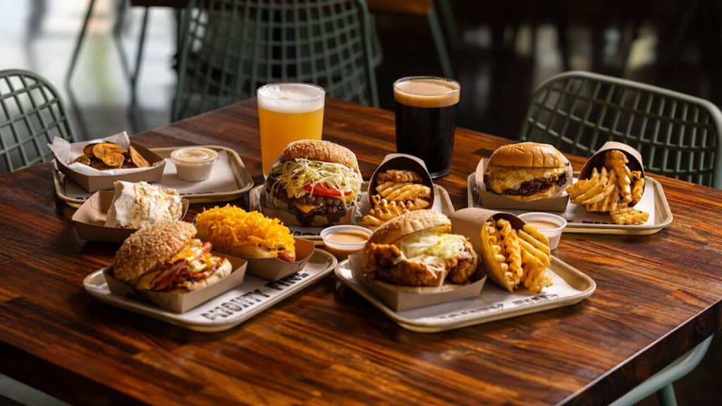 an assortment of burgers, fries, and chicken sandwiches on a table 