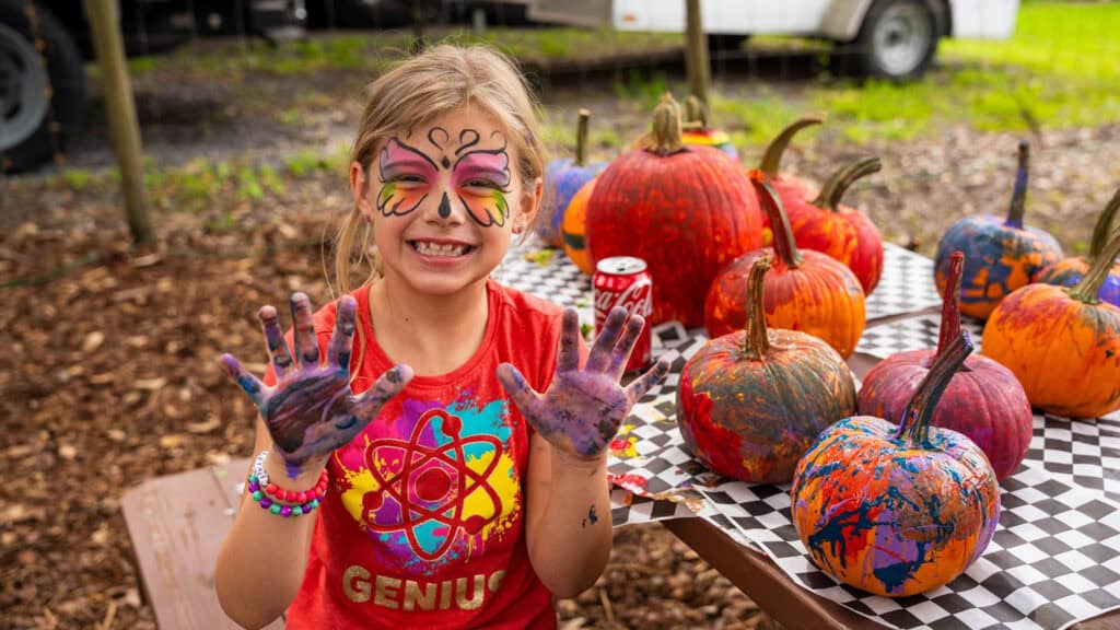 a young kid paints pumpkins 