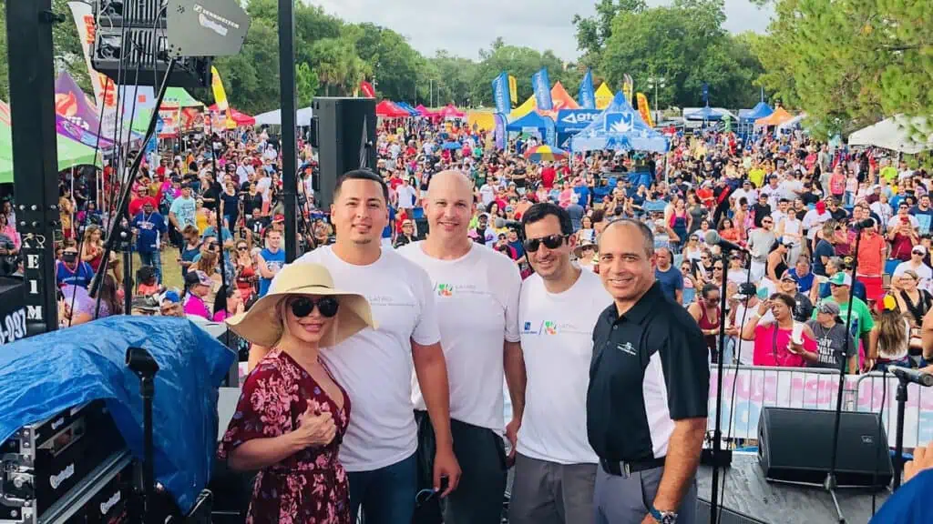 a group of people pose on stage at a waterfront festival