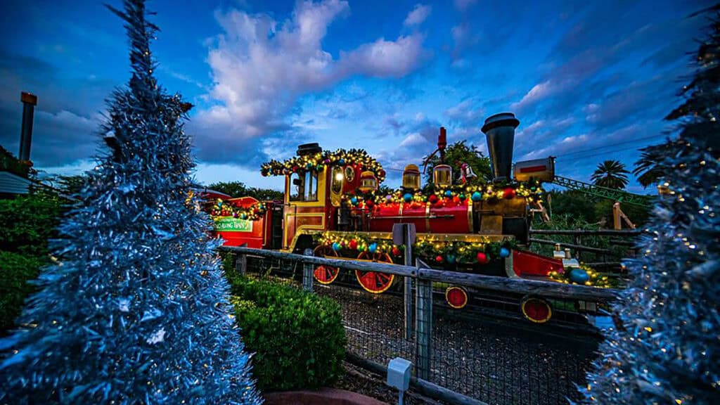 a train surrounded by Christmas lights at an amusement park 