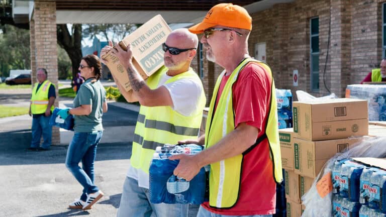 volunteers help load cars with essential items such as food and water