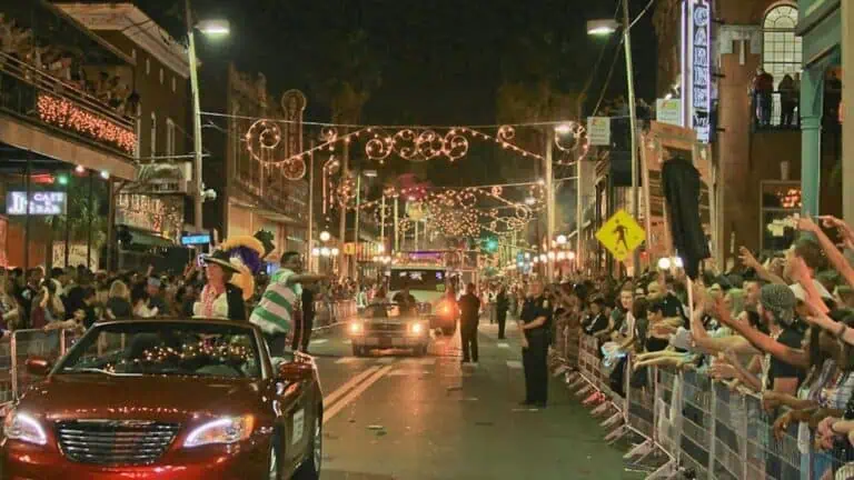 people sit in cars during a big parade