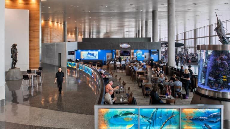 people gather for dinner at a restaurant inside an airport terminal. An aquarium is featured in the right corner of the photo