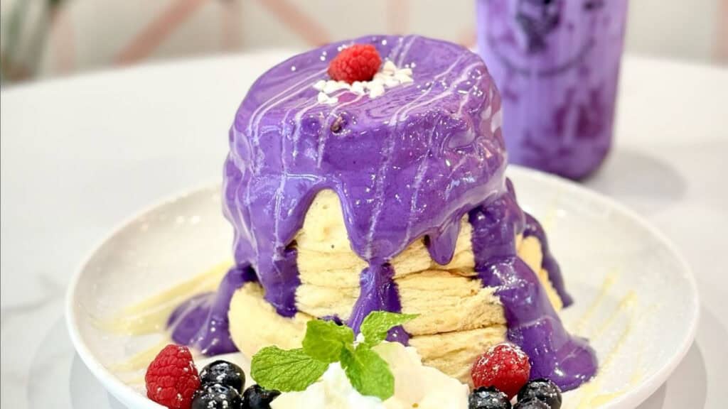 a stack of fluffy pancakes covered in a purple ube flavor