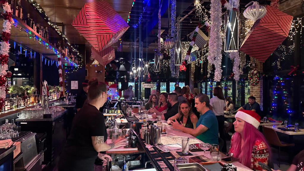 multiple guests gather at a bar covered in Christmas decorations