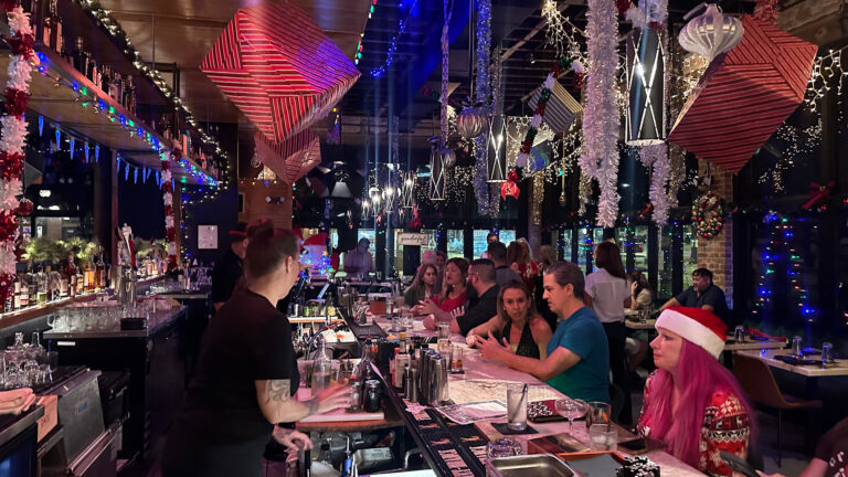 multiple guests gather at a bar covered in Christmas decorations