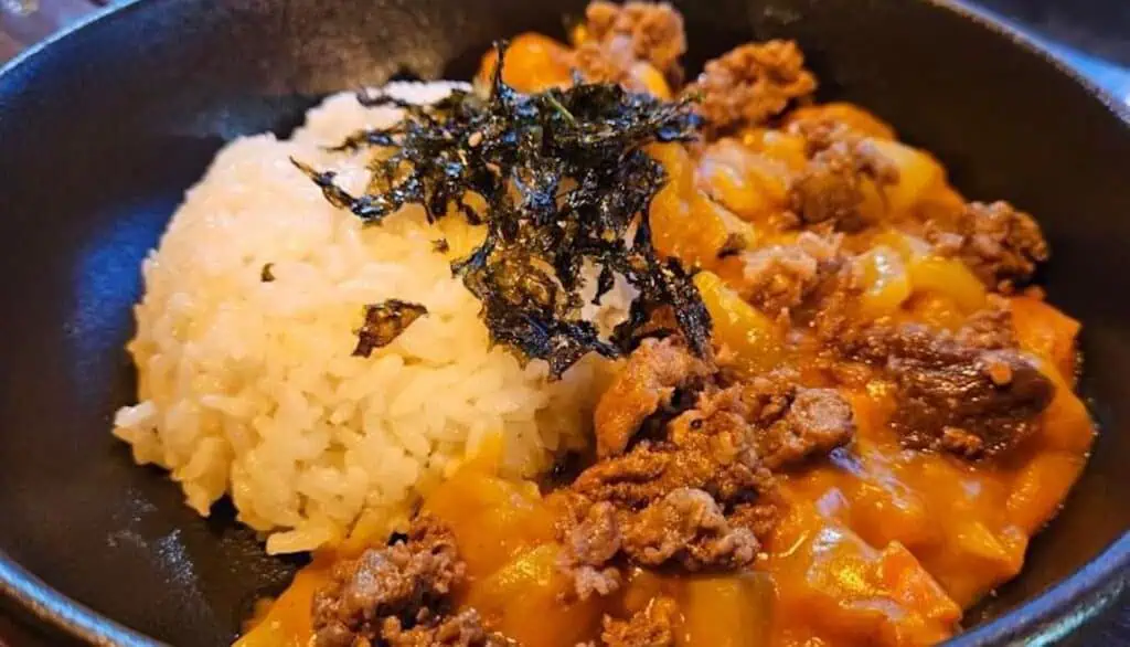 a bowl of rice with curry ad chicken