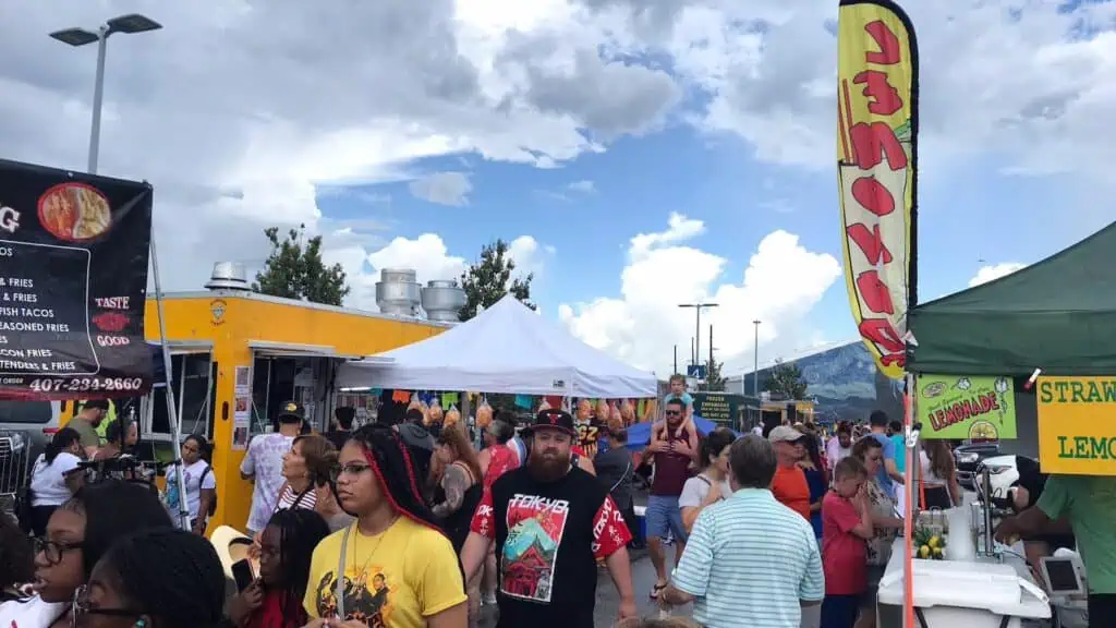 a huge food truck event with multiple people shopping around