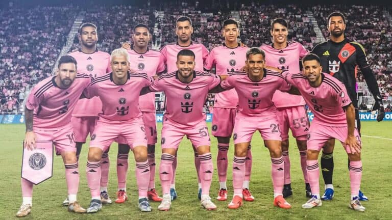 a group of soccer players on the field in pink jerseys