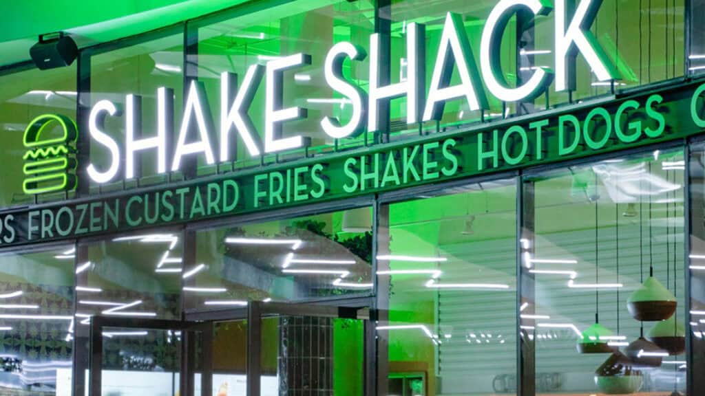 exterior of a burger restaurant with green lights behind the signage