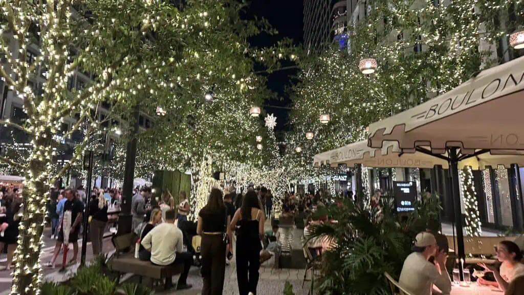 people dining under string lights in a shopping district 