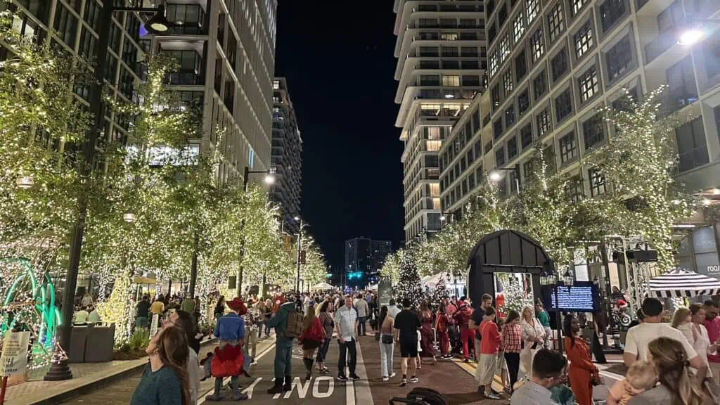 people walking on a sidewalk covered in lights