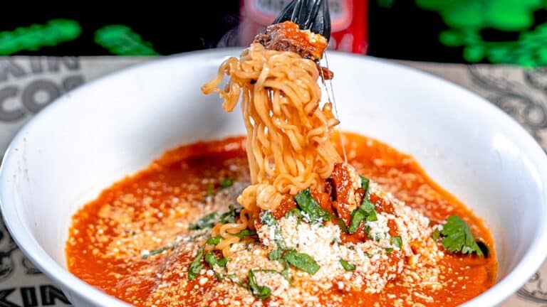 a bowl of ramen with multiple garnishments on top. Chopsticks twirl noodles out of the bowl