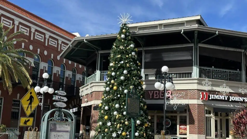 A Christmas tree in front of a brick building with multiple restaurants and offices in the plaza