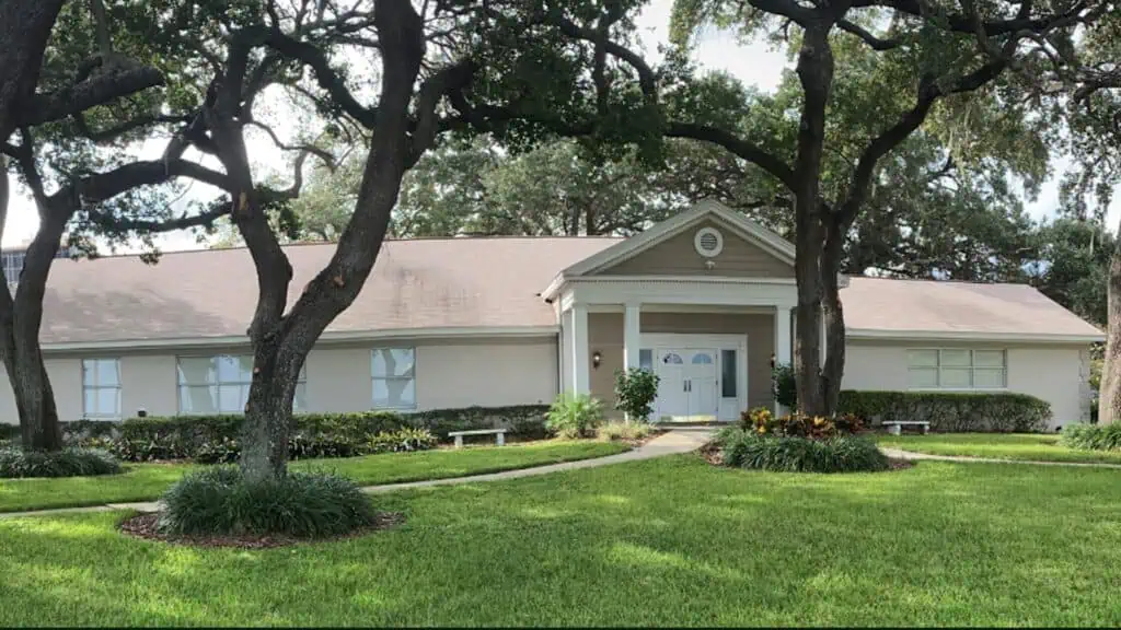 Exterior of a clubhouse on a sunny day surrounded by trees