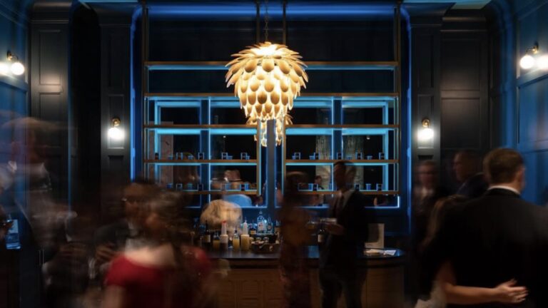 Interior of a bar with a chandelier over a blue lit dresser