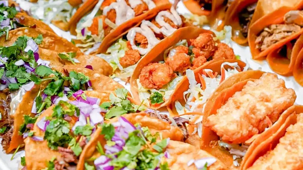 a platter of tacos featuring fresh seafood tacos drizzled with sauce 