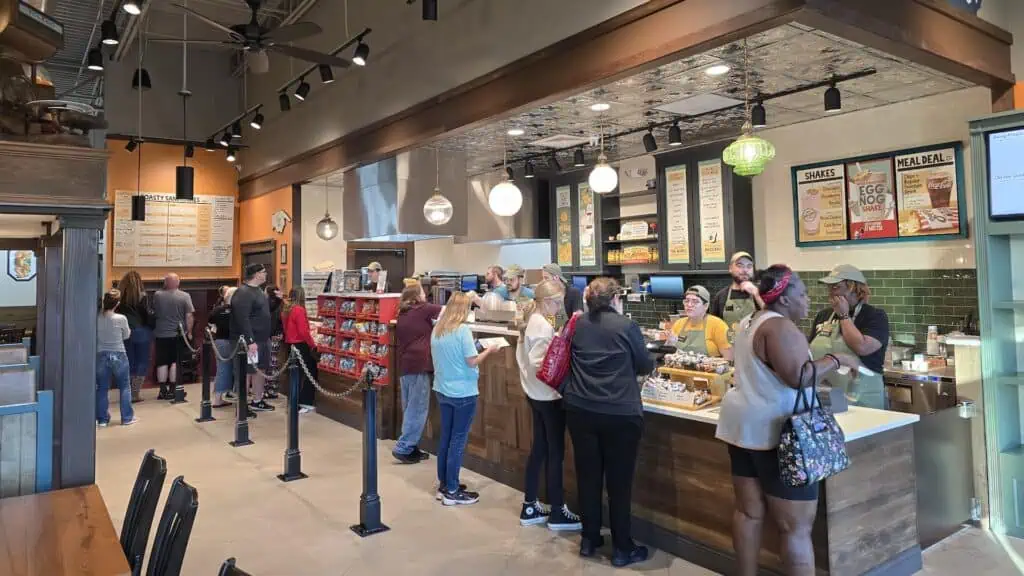 inside a sandwich shop with people lined up at a counter to order