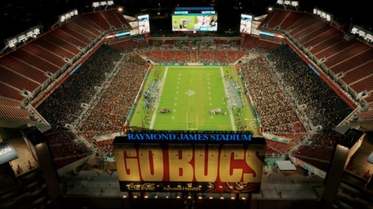 Aerial view of a football stadium at night. A large "GO BUCS" sign is visible