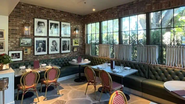 interior of a pub with green booths and large windows allowing ample natural light in. It has the feel of a cozy english cottage