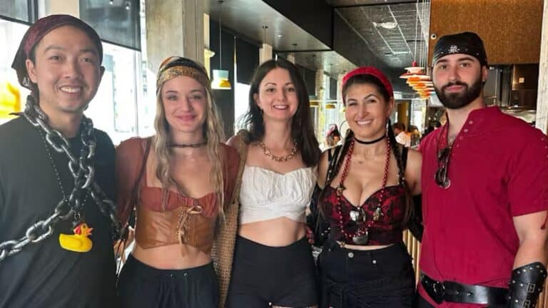 a group of 5 people dressed in pirate costumes pose for a photo inside of a restaurant