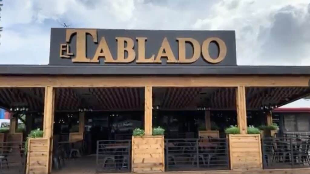 outside a restaurant with a wooden sign over the outdoor patio