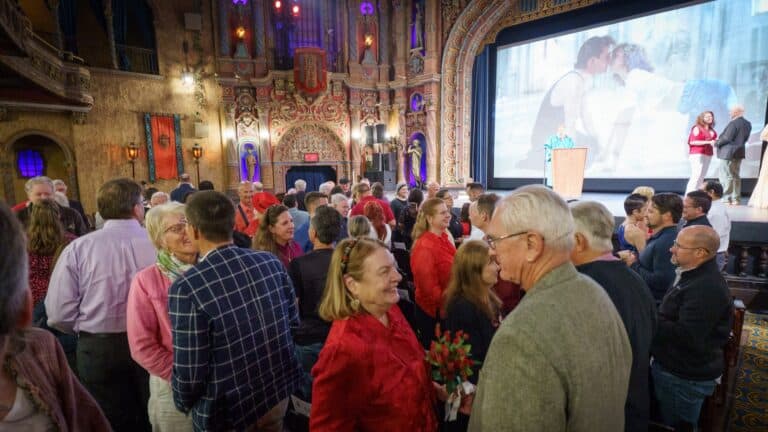 A large group of people embrace inside a historic movie theatre