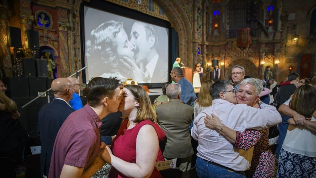 A large group of people embrace inside a historic movie theatre