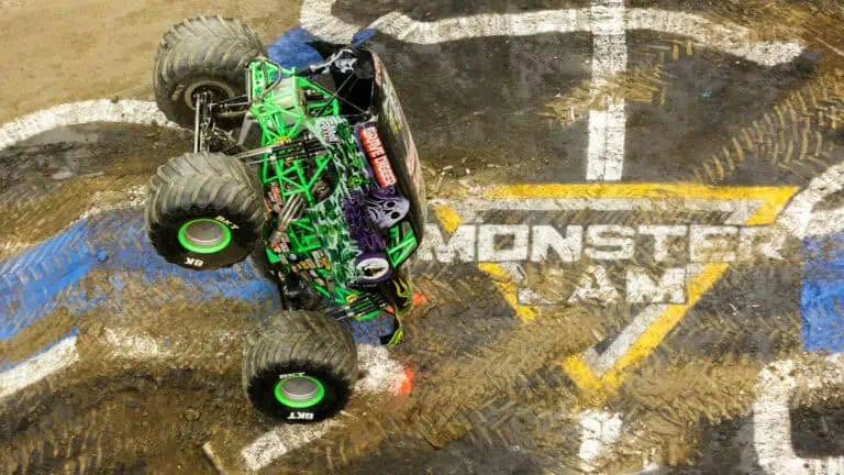 A vibrant green monster truck, "Grave Digger," tipped on its side during a muddy Monster Jam event.