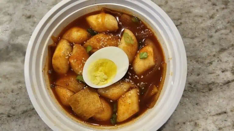 a bowl of soup with an egg on top and marinated chicken