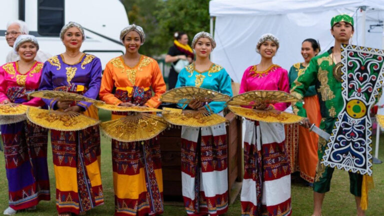 People wearing cultural attire and holding large fans