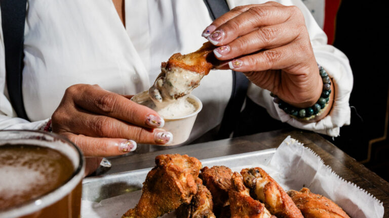 A person eating wings at Blind Goat in Tampa