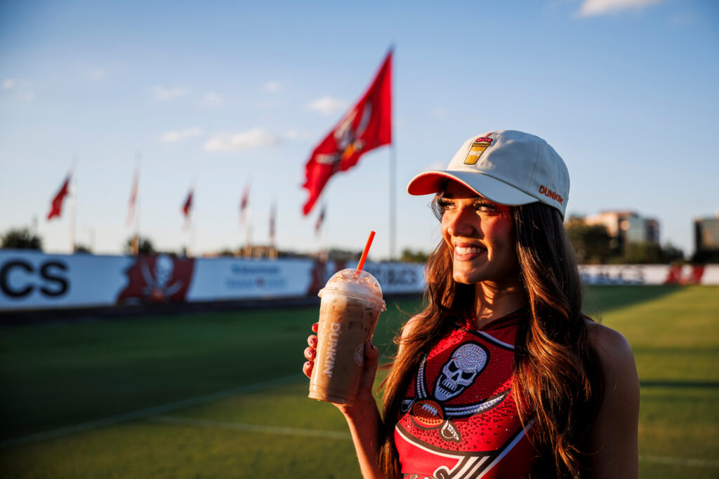 A person wearing a Dunkin Donuts by Tampa Bay Buccaneers hat